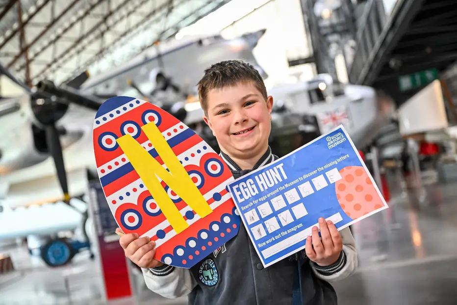 Child holding an easter egg cutout and a sheet of paper where they have written the eggs they have found